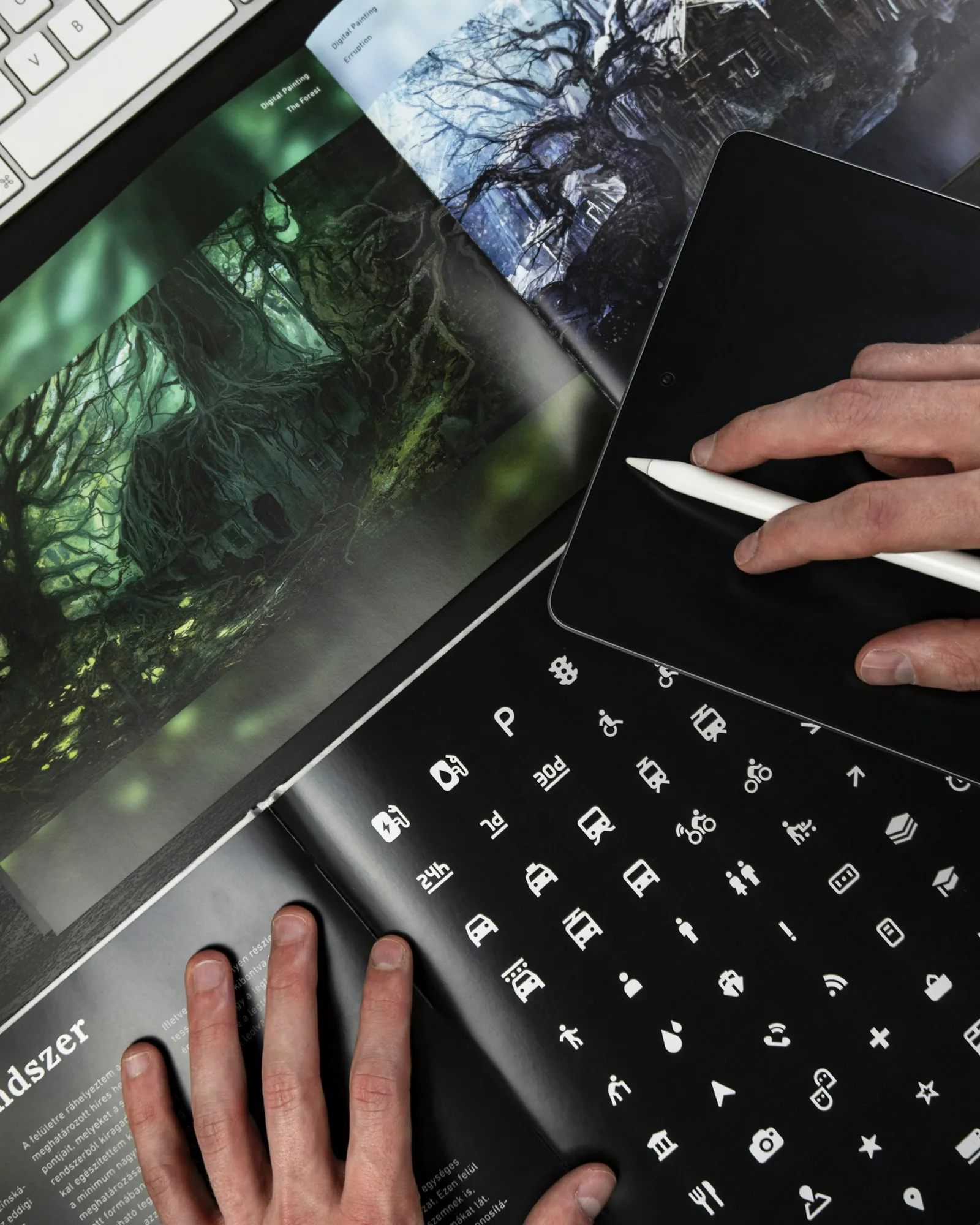 Graphic designer using a stylus beside a book of visual design references